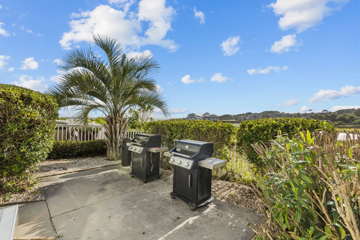 Set among lush palm trees and greenery, this image shows two outdoor grills ready for use, suggesting opportunities for group gatherings, barbecues, and cheerful socializing in a tropical setting.