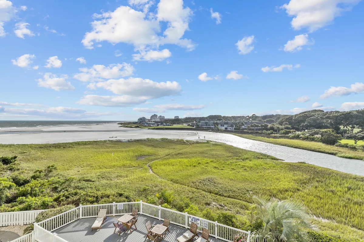 A sweeping view across expansive water and vibrant marshland with distant buildings under a dramatic sky. The setting is tranquil, natural, and encourages outdoor exploration and peaceful moments.