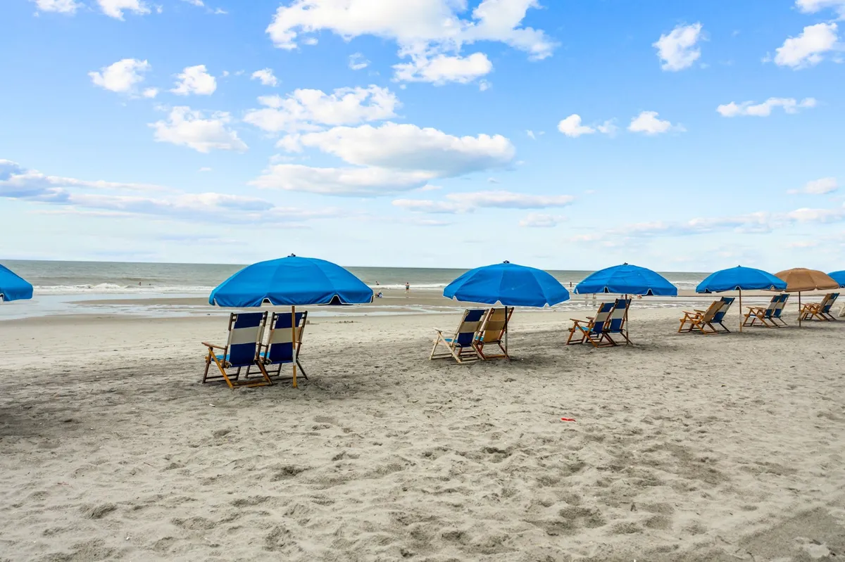The scene features beach chairs and umbrellas set up on the sand, facing the gentle ocean and open sky. The tranquil mood suggests leisurely days spent outdoors, even in the mild winter climate of Myrtle Beach.