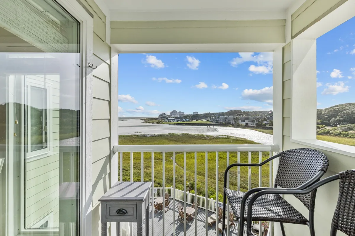 A peaceful balcony scene overlooking sparkling water and green landscape, with a railing perfect for leaning and taking in the sights. The setting is tranquil, inviting quiet moments with a book or morning coffee while soaking up sunrise or sunset views.